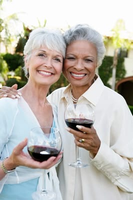 Two smiling women enjoying drinks outdoors