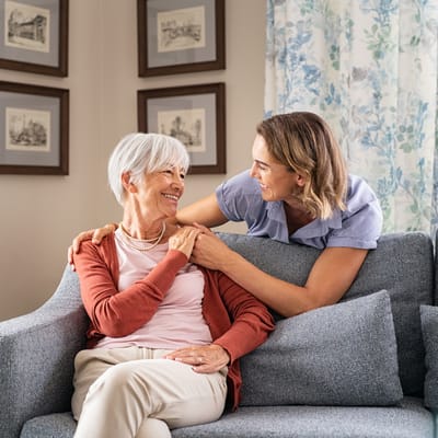 Caregiver and resident sharing a joyful moment on a sofa