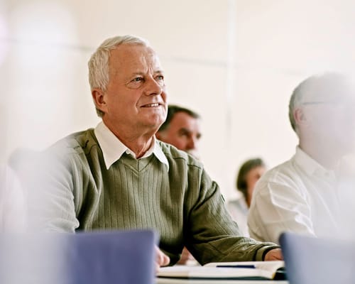 An older gentleman attending a class in a bright room