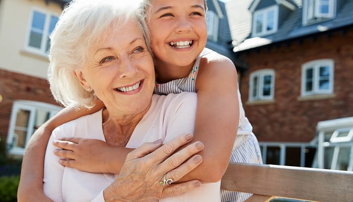 An elderly woman and a girl smiling outdoors