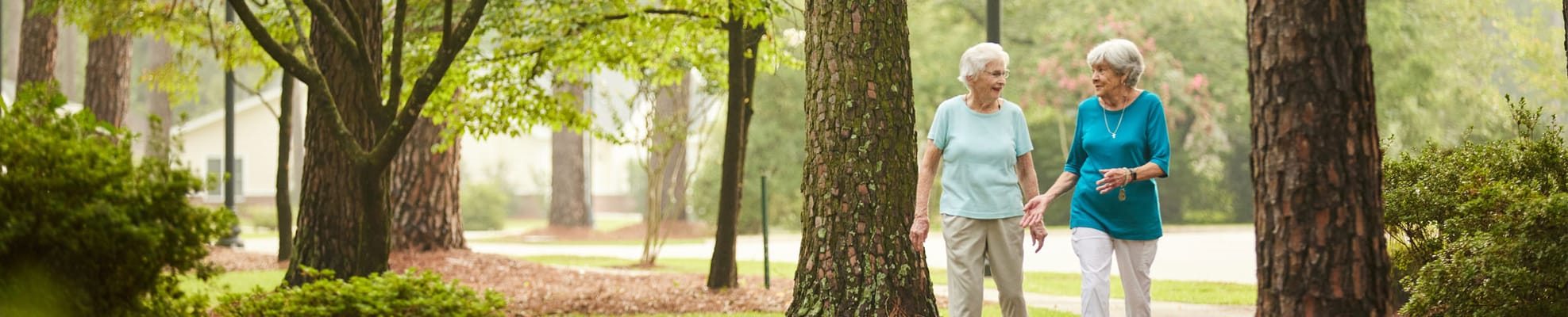 Two seniors walking in a tranquil outdoor space