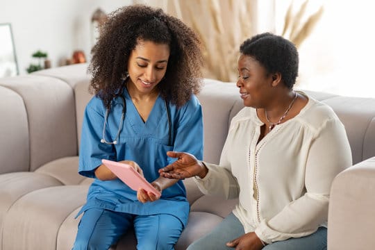 A caregiver showing a tablet to a resident in a common area