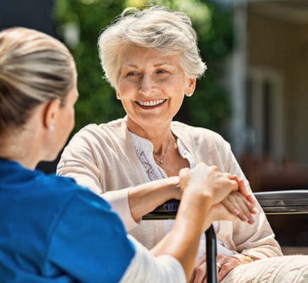 A resident smiling and interacting with staff outdoors