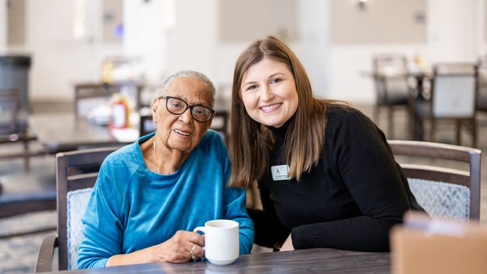 Resident and staff member smiling in a common area