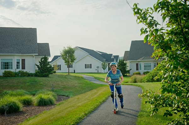 Resident riding a scooter on a pathway between homes