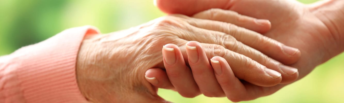 Hands of a caregiver and a senior resident