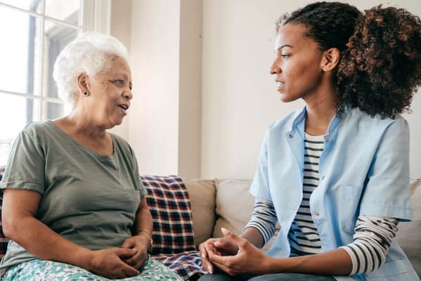 A caregiver talking to a resident in a bright room