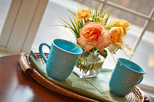 Two blue mugs and a flower arrangement on a tray