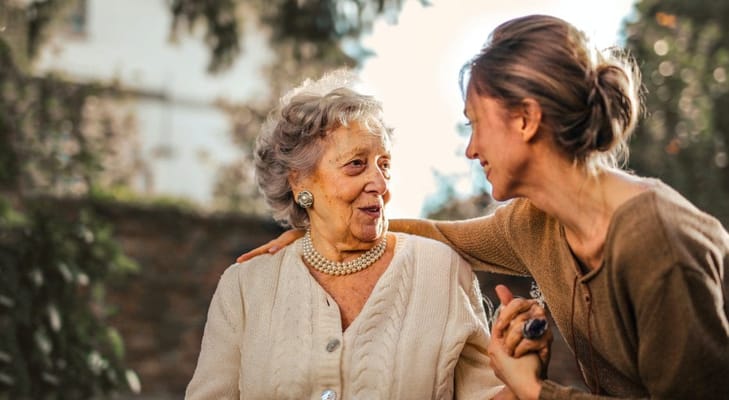 A caregiver and a resident sharing a joyful moment outdoors