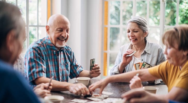 Residents enjoying a card game in a bright common area