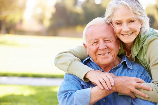 Elderly couple smiling together in a garden