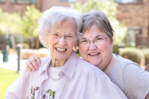 Two women, a resident and staff member, smiling outdoors