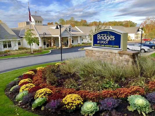 Facility sign in front of the building with flower beds.