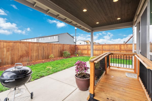 View of a covered patio with a grill and garden
