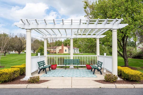 Outdoor seating area with a pergola and green lawn.