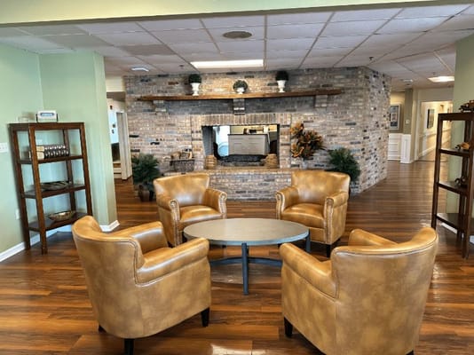 Lounge area with four leather chairs and a coffee table in front of a brick fireplace.