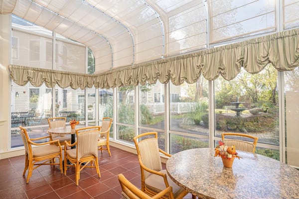 Bright sunroom with tables and chairs overlooking a garden