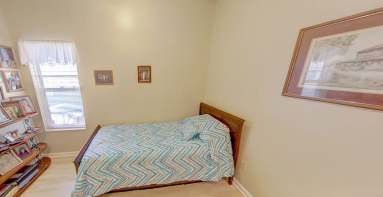 A bedroom featuring a single bed, patterned blanket, and personal photos on the wall.