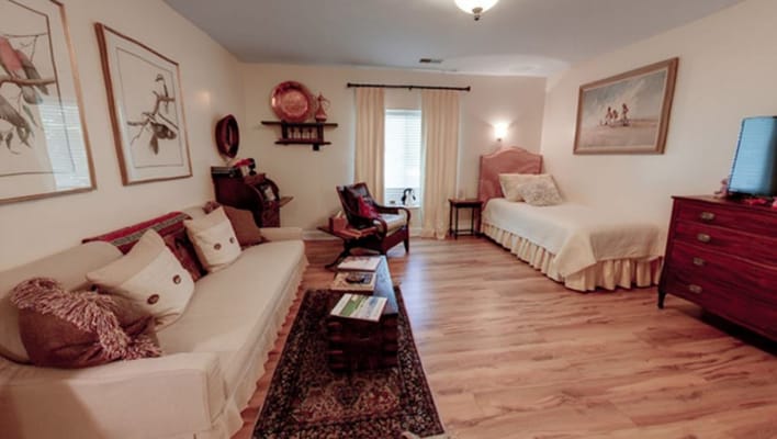 A cozy living room with a sofa, bed, and artwork.