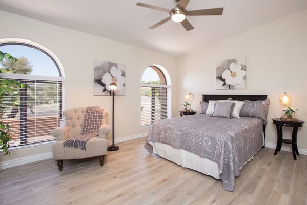 A well-furnished bedroom with a bed, armchair, and window.