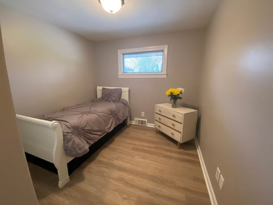 A neatly arranged private resident room with a bed and flowers