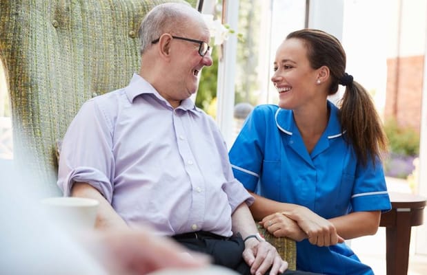 A caregiver laughing with a senior resident in a cozy setting.