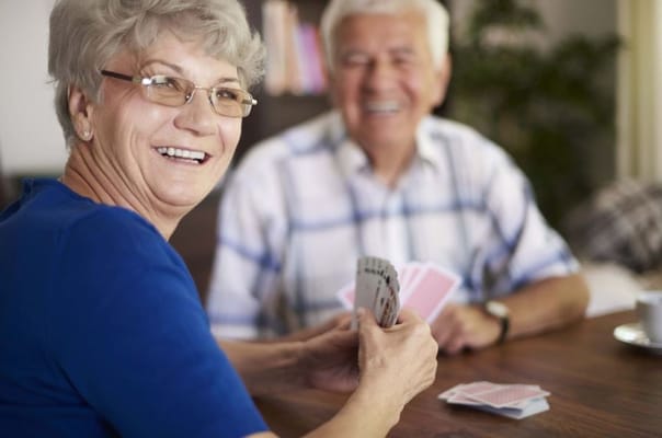 Two seniors smiling while playing cards at a table