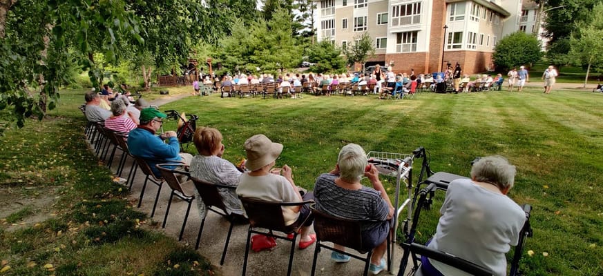 Residents enjoying an outdoor concert in a grassy area