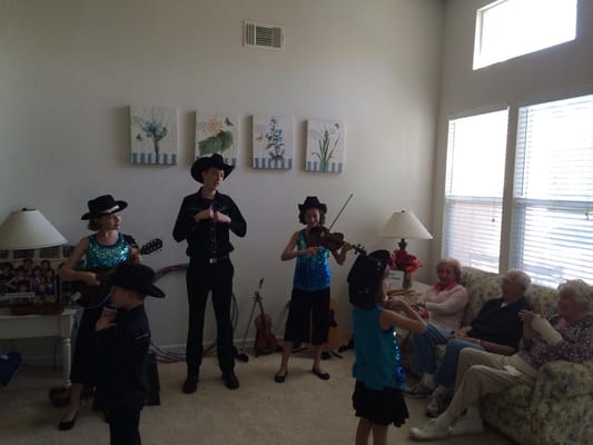 Children performing in sparkly costumes for residents