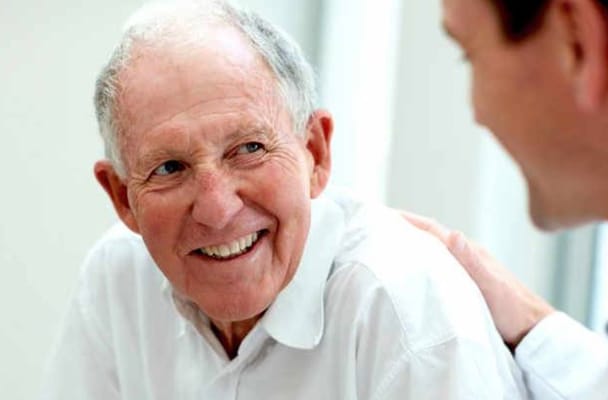 A senior man smiling while engaged in conversation.