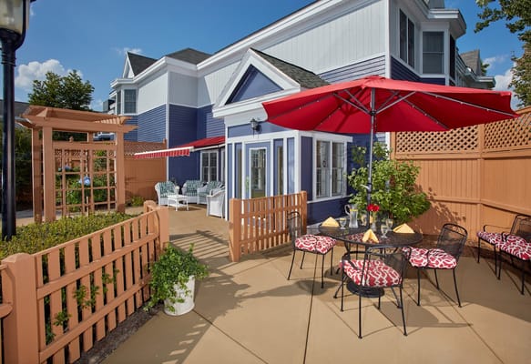Outdoor patio with seating and umbrellas at Heights Crossing Assisted Living