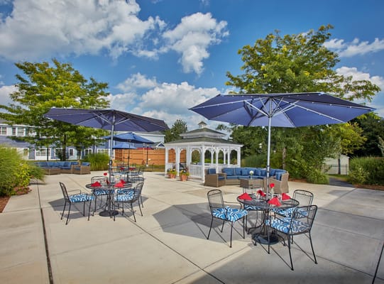 Patio area with seating and umbrellas at Heights Crossing Assisted Living.