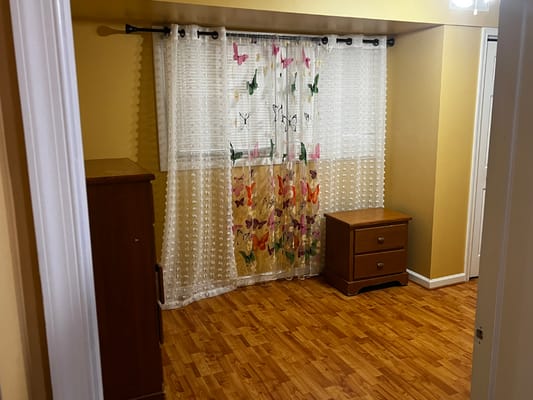Spacious living area with a butterfly curtain and wooden furniture.