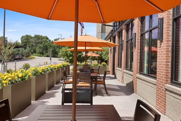 Outdoor seating area with orange umbrellas and flowers