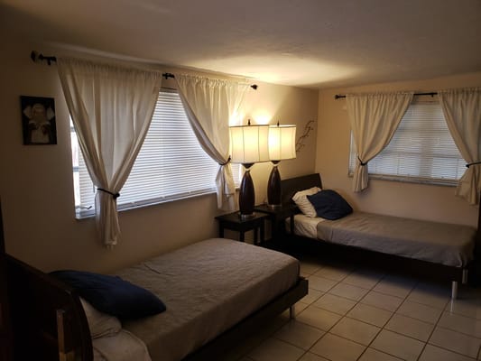 A spacious bedroom with two beds and natural light from windows.