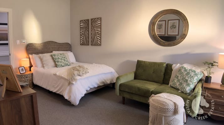 A comfortable bedroom with a bed, green sofa, and decorative elements.
