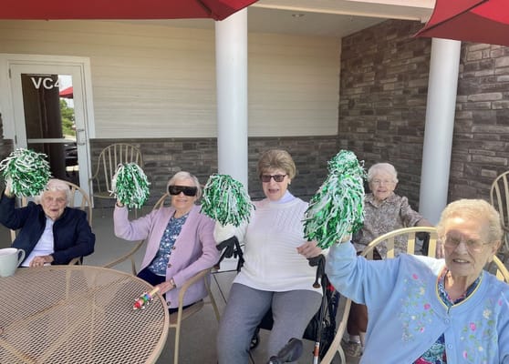 Residents cheerfully holding pom-poms in an outdoor setting
