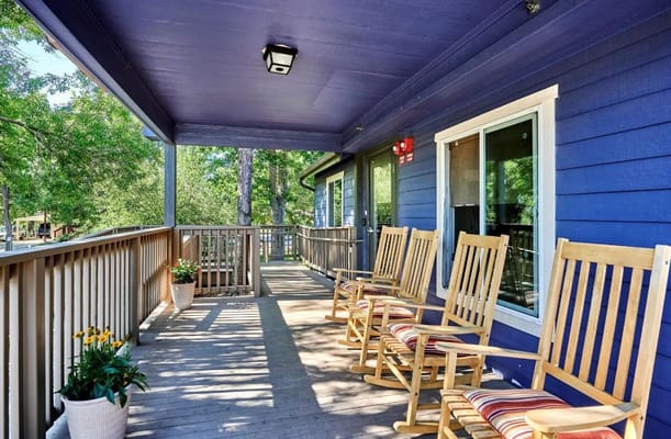 A porch with rocking chairs and greenery