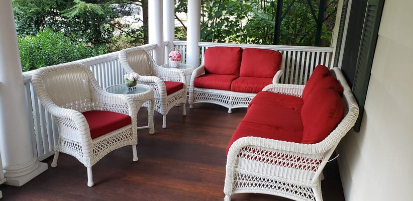 White wicker patio furniture with red cushions on a porch