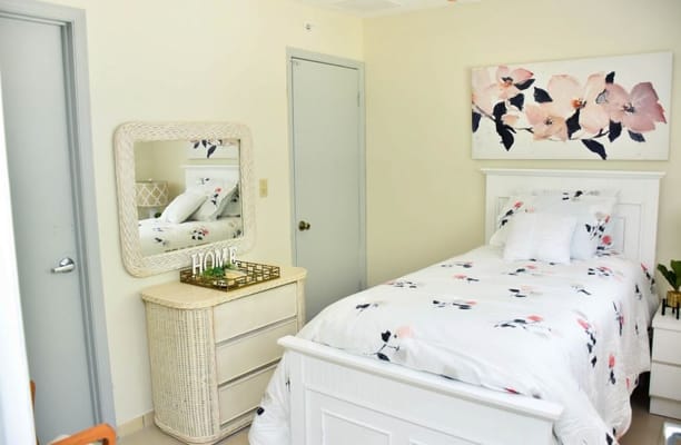 Bright and elegantly decorated bedroom with floral bedding and a mirror.