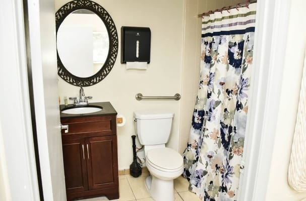 A modern bathroom with a sink, toilet, and colorful shower curtain.