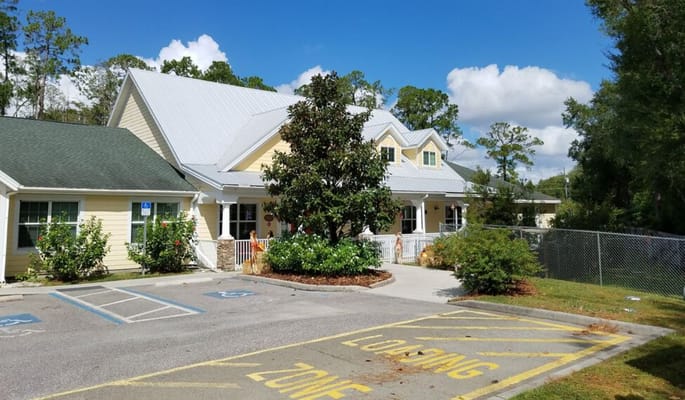 Exterior view of Magnolia Manor with trees and parking lot