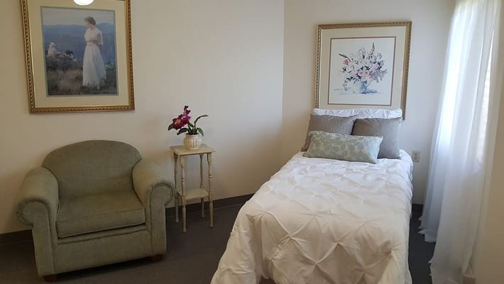 A private resident room with bed and chair