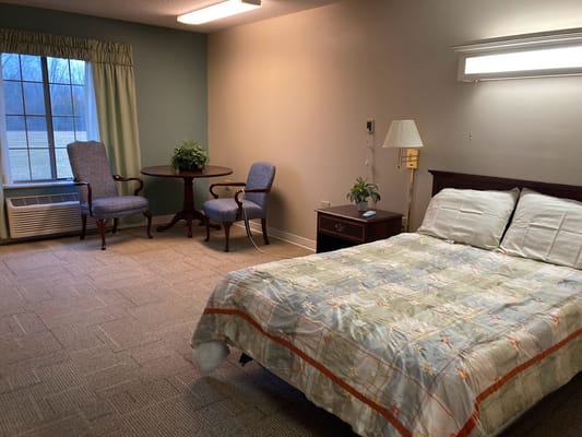 A well-furnished resident room with a bed and seating area