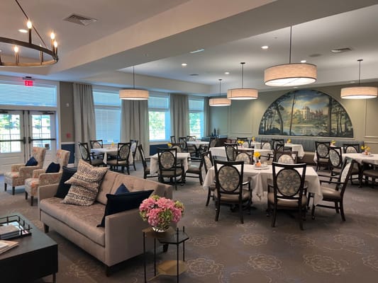 Cozy dining area with tables and chairs, floral decor, and a mural