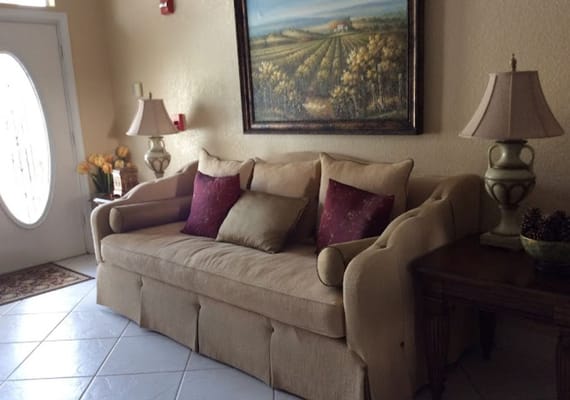 A cozy living room with a beige sofa, decorative pillows, and a painting on the wall.