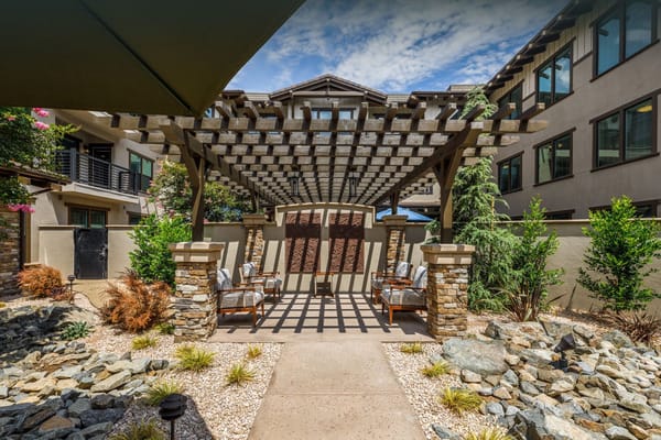 Outdoor seating area with shaded shelter and landscaping