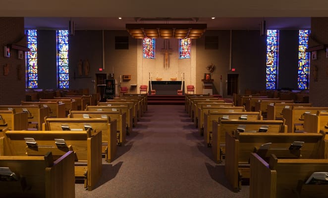 Interior view of the chapel with wooden pews and stained glass windows