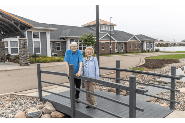 Two seniors standing on a bridge in the garden area