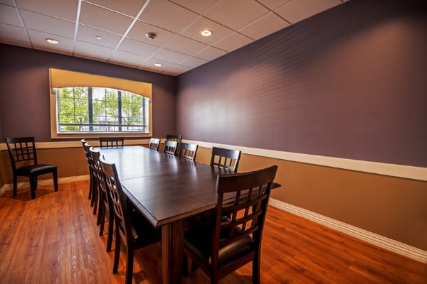 A spacious meeting room with a long table and chairs, featuring a window.